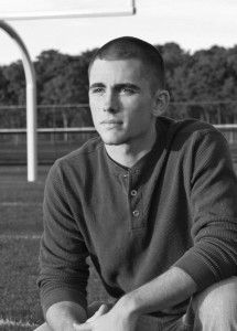 Picture of a high school senior, in black and white, posing on the football field