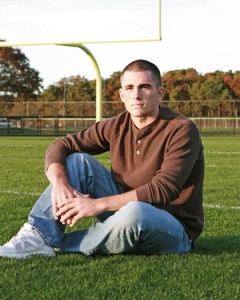 Photo of a high school senior sitting on football field