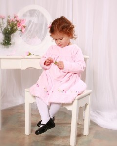 A little girl in a pink dress, posing for a photo portrait